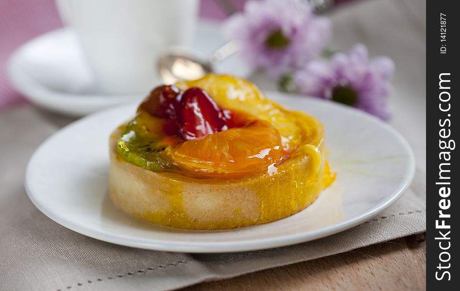 Fruitcake mini on a plate with fresh flowers on the background