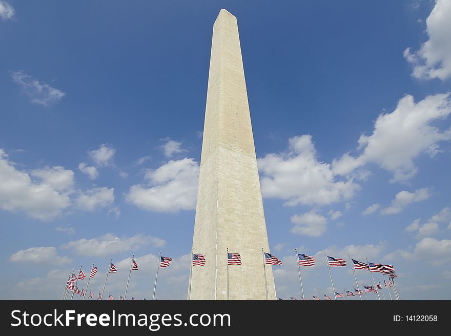 Washington monument in Washington DC against blue sky with american flags circling it