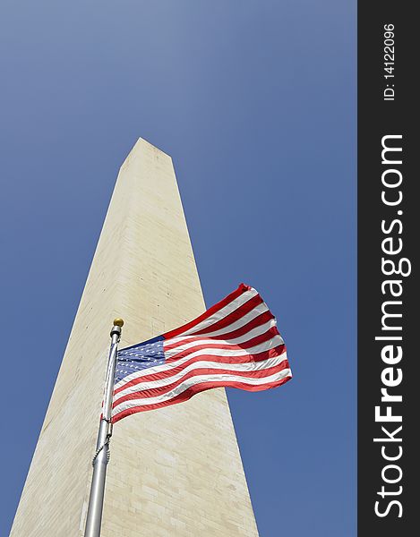 Washington monument in Washington DC against blue sky with american flag in front. Washington monument in Washington DC against blue sky with american flag in front