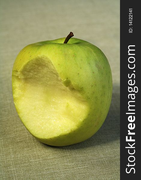 Bitten green juicy apple on linen tablecloth. Bitten green juicy apple on linen tablecloth