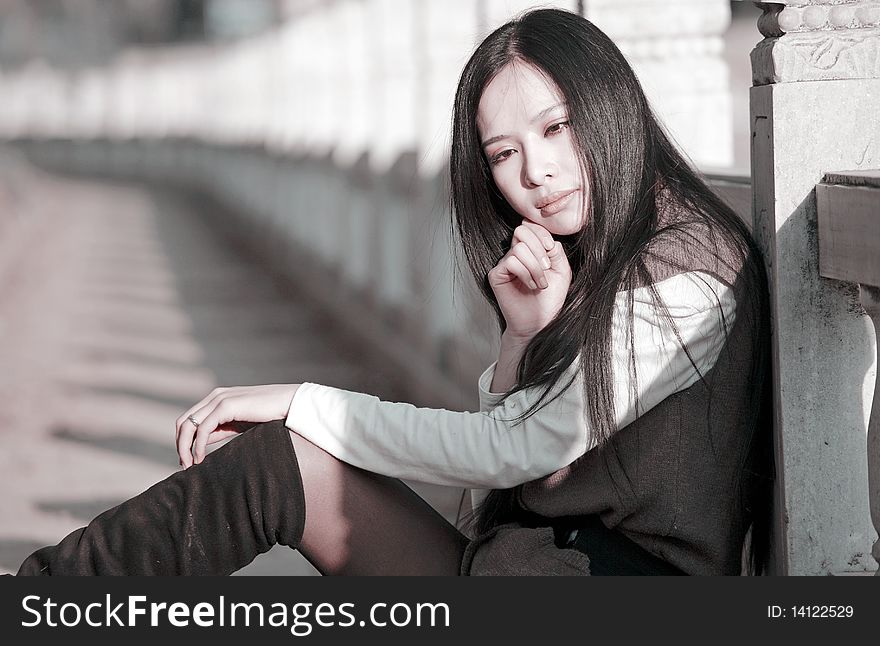 Young Asian woman is sitting outdoors and pondering in spring. Young Asian woman is sitting outdoors and pondering in spring.