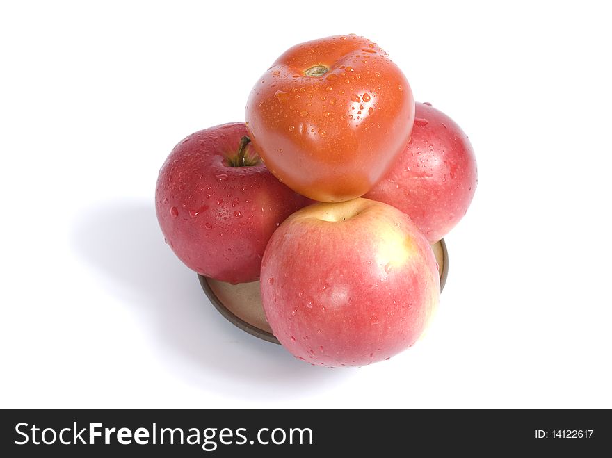 Ripe apples and red tomato coverd with drops of water on a plate, isolated on the white background. Ripe apples and red tomato coverd with drops of water on a plate, isolated on the white background