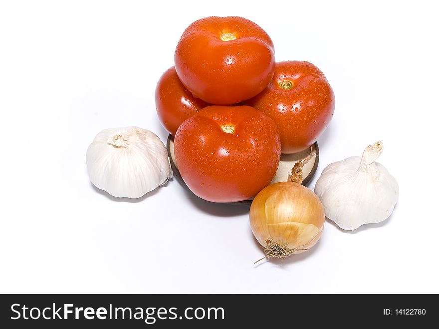 Ripe red tomatoes on a plate, onion and garlic, isolated on the white background. Ripe red tomatoes on a plate, onion and garlic, isolated on the white background