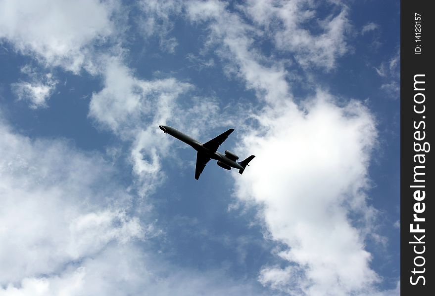 A jet airplane flying under small clouds while coming in to land. A jet airplane flying under small clouds while coming in to land.