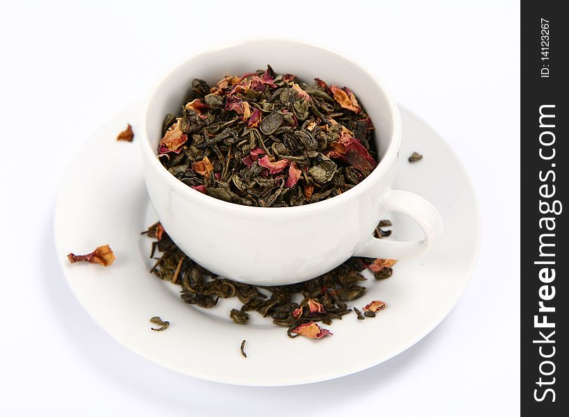 Cup filled with dried green tea leaves and rose petals