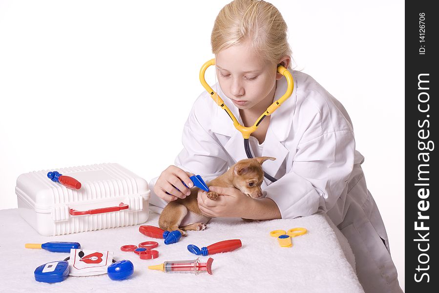 Young Blond Girl pretending to be a veterinarian uses tweezers on the puppy's paw. 5569. Young Blond Girl pretending to be a veterinarian uses tweezers on the puppy's paw. 5569