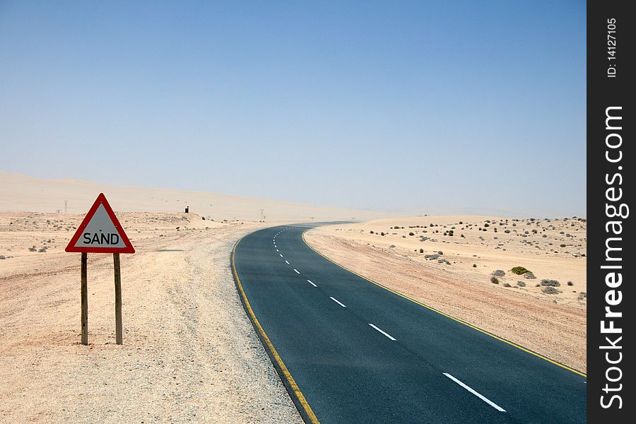 Warningsign SAND beside desolate highway against dusty blue sky, Namibia. Warningsign SAND beside desolate highway against dusty blue sky, Namibia.