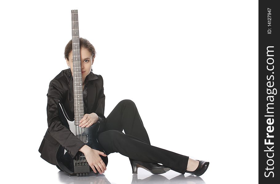 Seated girl posing in studio with a black electric bass guitar. Isolated on white background. Copy space available. Seated girl posing in studio with a black electric bass guitar. Isolated on white background. Copy space available