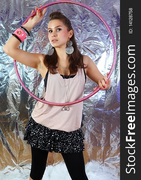 Shot of young and beautiful woman wearing pink shirt and black dress with glitter stars. She is holding pink glitter hoop. Shiny reflective background (Professional makeup and hair style). Shot of young and beautiful woman wearing pink shirt and black dress with glitter stars. She is holding pink glitter hoop. Shiny reflective background (Professional makeup and hair style).