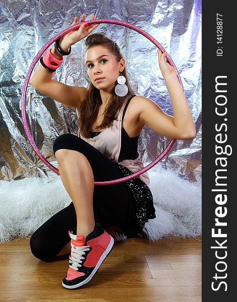 Shot of young and beautiful woman wearing pink shirt and black dress with glitter stars. She is holding pink glitter hoop. Shiny reflective background (Professional makeup and hair style). Shot of young and beautiful woman wearing pink shirt and black dress with glitter stars. She is holding pink glitter hoop. Shiny reflective background (Professional makeup and hair style).