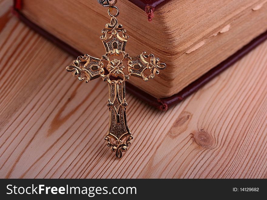 Religion. A cross with a book against a wooden table.