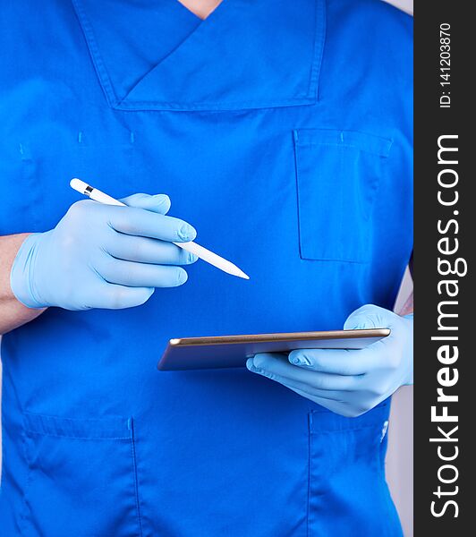 Doctor in blue uniform and latex gloves holding an electronic tablet