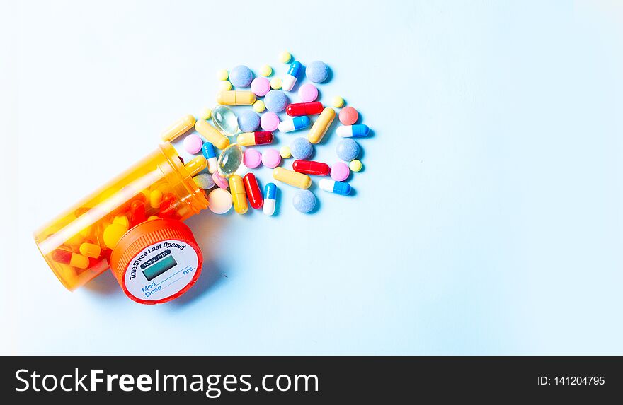 Pile of medical pills falling from bottle on blue background banner with copy space. Pile of medical pills falling from bottle on blue background banner with copy space