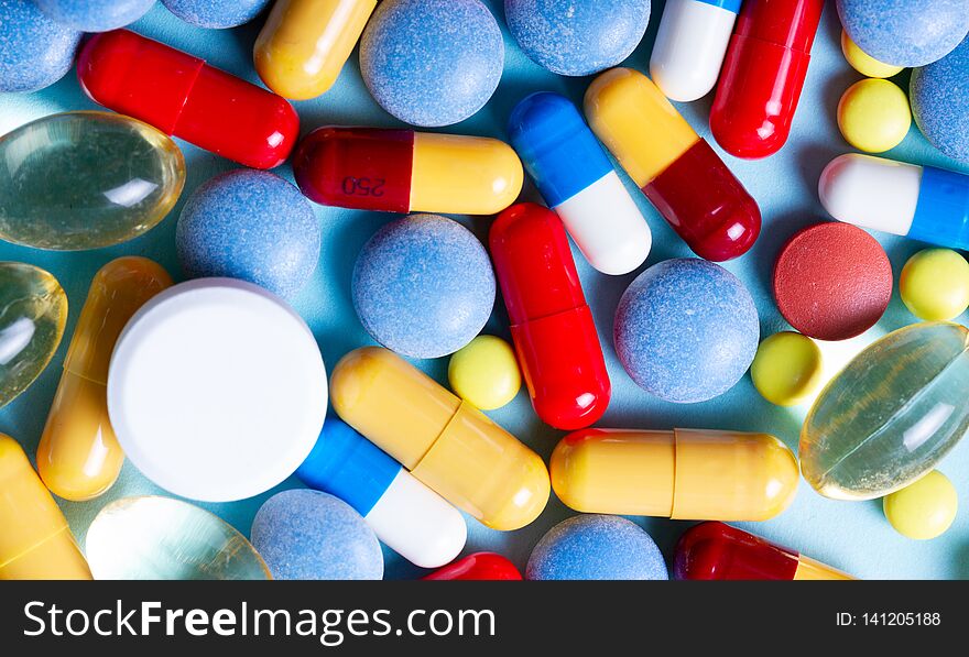 Pile of colorful medical pills on blue background, top view banner. Pile of colorful medical pills on blue background, top view banner