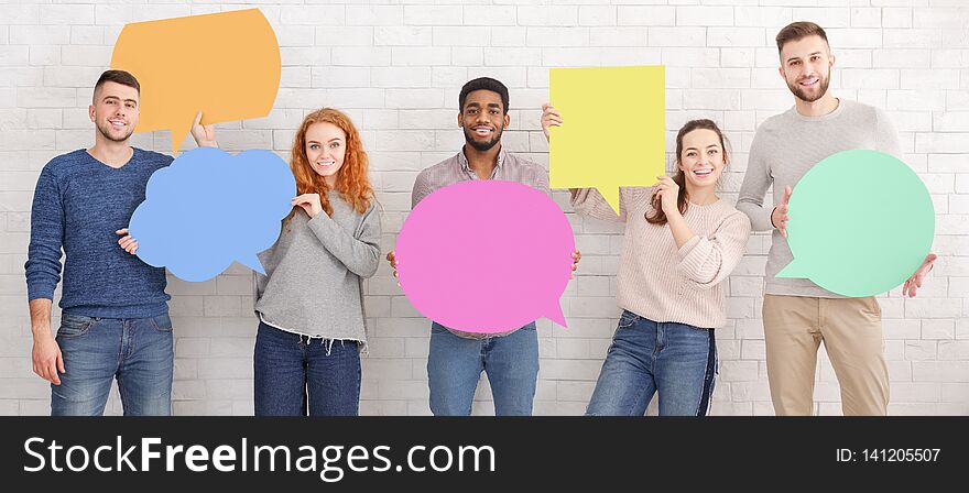 Friends Holding Empty Speech Bubbles Over White Wall