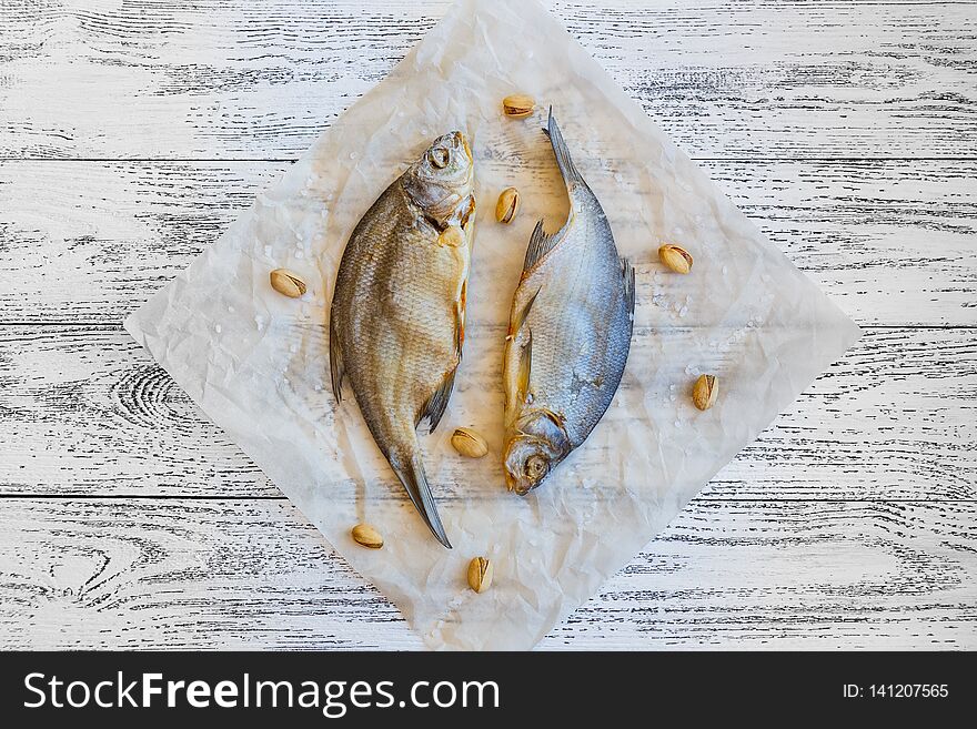 Two dried fish bream lie on a light wooden table
