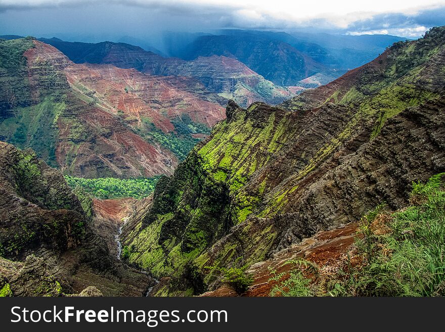 Spectacular view of Waimea Canyon State Park on a cloudy day with waterfall and river, Kauai, Hawaii