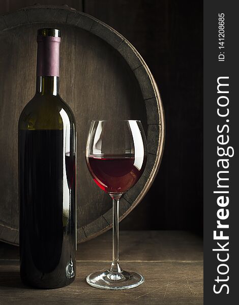 Glass and bottle of red wine on wooden background. Wine background. Glass and bottle of red wine on wooden background. Wine background