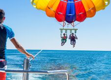 Happy Couple Parasailing On Miami Beach In Summer. Couple Under Parachute Hanging Mid Air. Having Fun. Tropical Paradise. Positive Royalty Free Stock Images