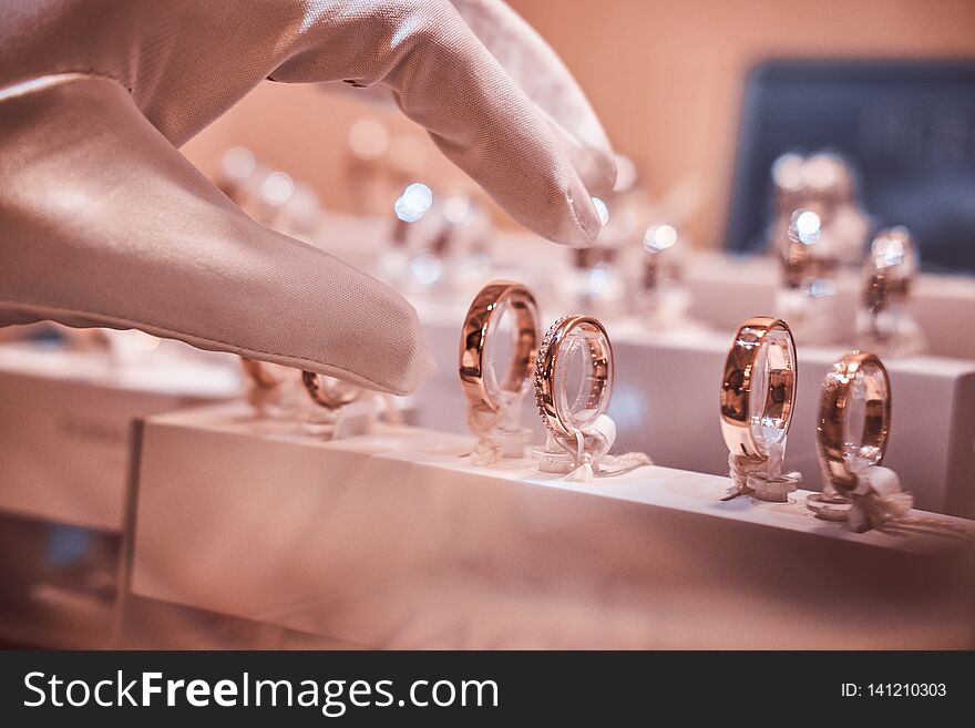 Hand in gloves takes to exclusive rings on the showcase of a jewelry store
