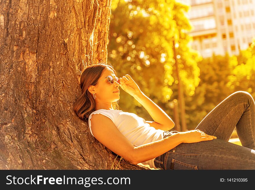 A young woman lying next to a tree and enjoying the sunshine