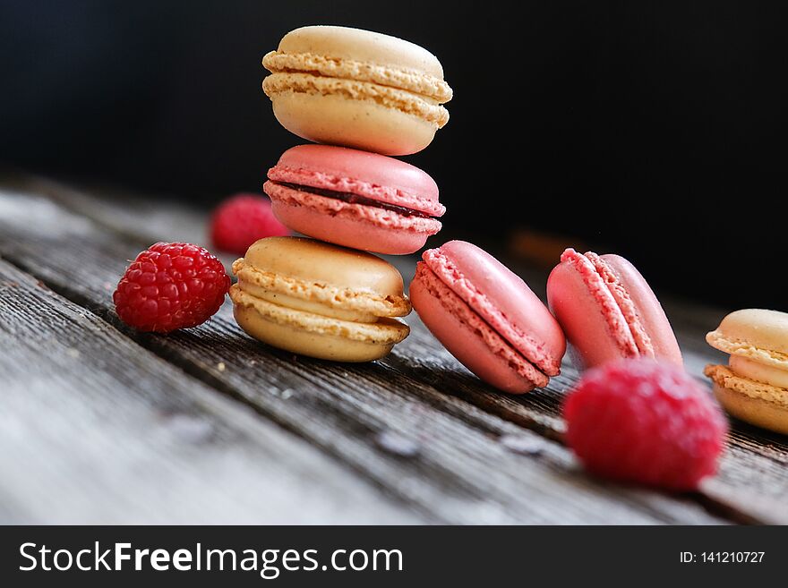 Colorful French macarons with raspberries on a table