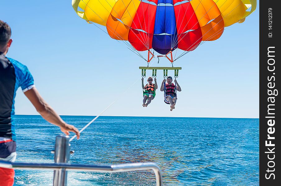 Happy couple Parasailing on Miami Beach in summer. Couple under parachute hanging mid air. Having fun. Tropical Paradise. Positive