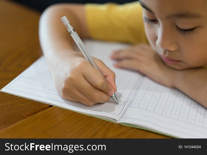 Little boy hand is writing homework at home. Education at home concept