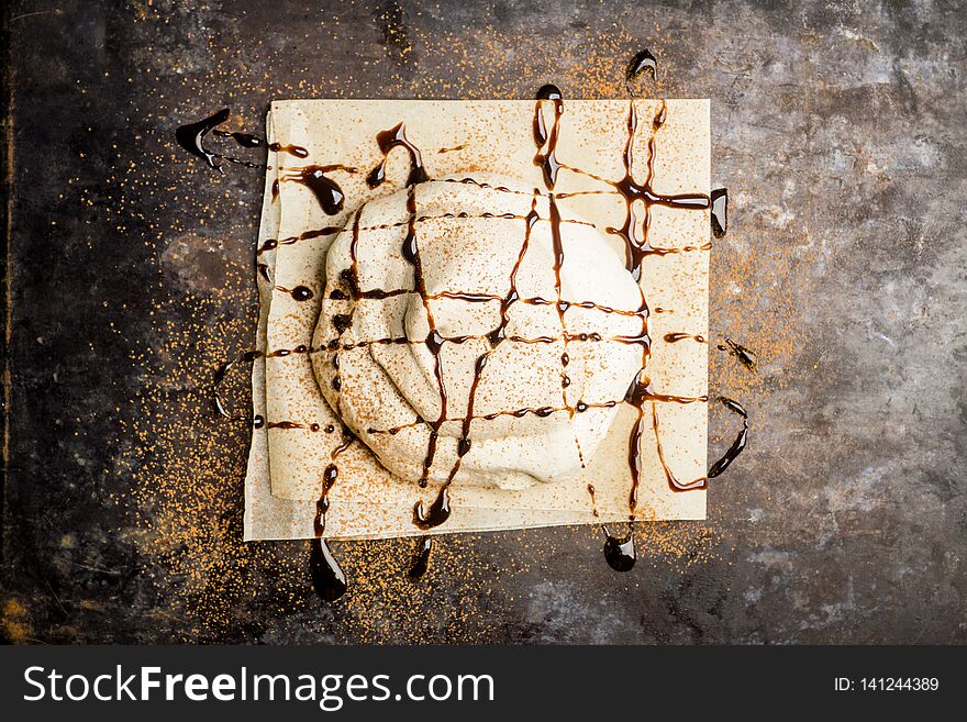 Chocolate meringue dessert decorated with glaze and chocolate powder. Selective focus.