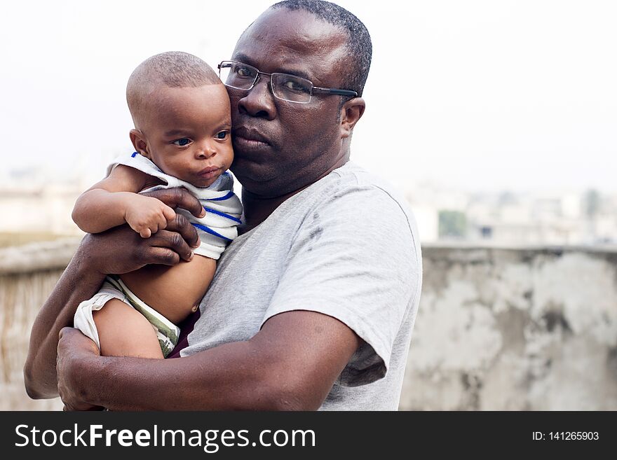 Middle aged men takes a picture with his baby while looking at the camera. Middle aged men takes a picture with his baby while looking at the camera