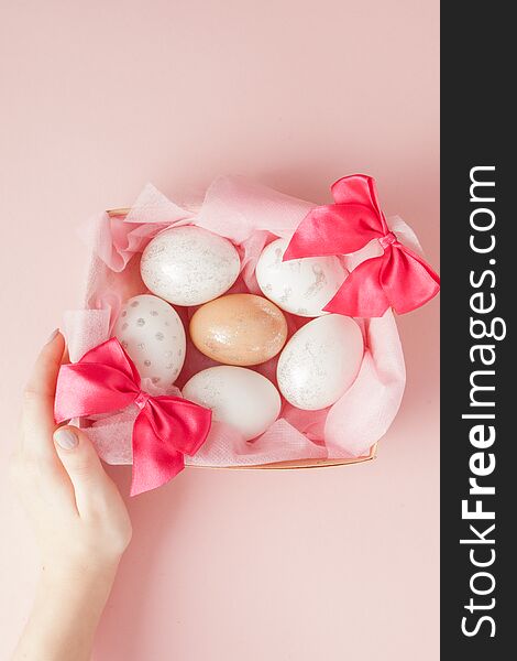 White Easter eggs in a nest on pink background. Design pastel tone in minimal flat lay.