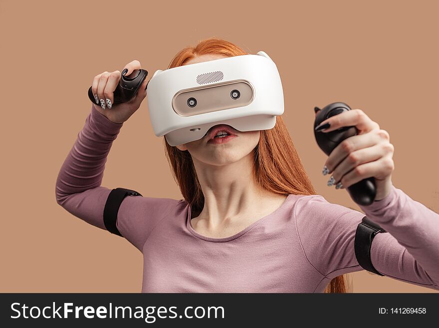 Emotional female with red long hair standing experiencing vertual reality headset for the first time. Generation of realistic images of alternative digital reality. Emotional female with red long hair standing experiencing vertual reality headset for the first time. Generation of realistic images of alternative digital reality