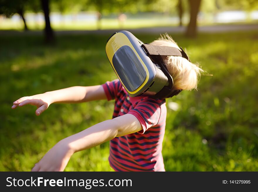 Little boy using virtual reality headset outdoor. VR, VR glasses, augmented reality experience