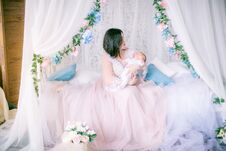 Young Mother In A Boudoir Dress With A Baby In Her Arms By The Canopy Bed Stock Photography