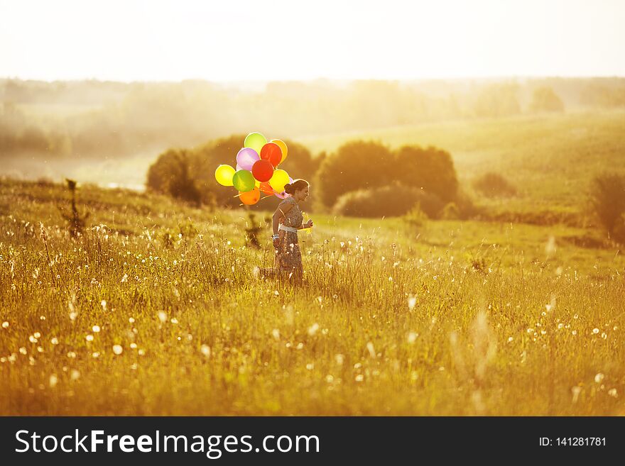 Young happy woman running across the field with balls