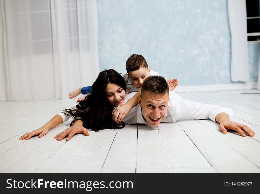 Young father have fun with daughter and son. Young family with children in white clothes.