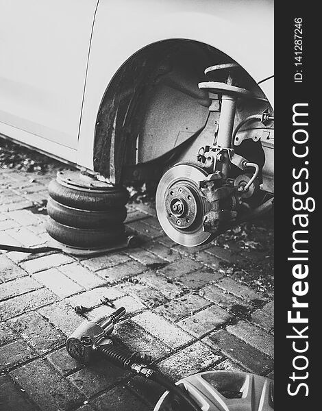 Car without wheel on service. Car tire replacement concept. Old style monochrome photo.
