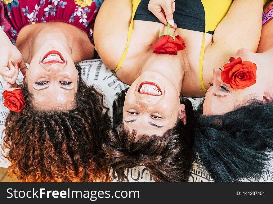 Playful group of young females friends at home together laughing and smiling. lay down on bed and taken from aerial view. make up