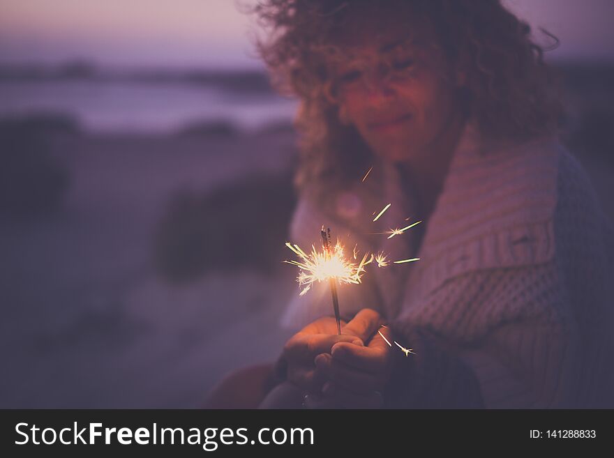 Single attractive woman defocused portrait taking alone sparkles light fireworks to celebrate new year or party event outdoor in alternative way with no friends around - sad and happy concept