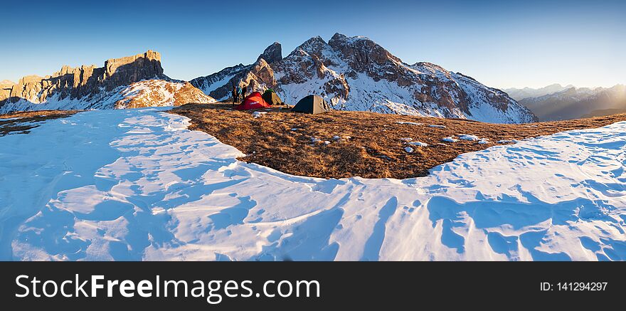 Winter camp, Sunny day, shining green and red  tent in the snow. Sleeping in the snow outside. Alps mountains