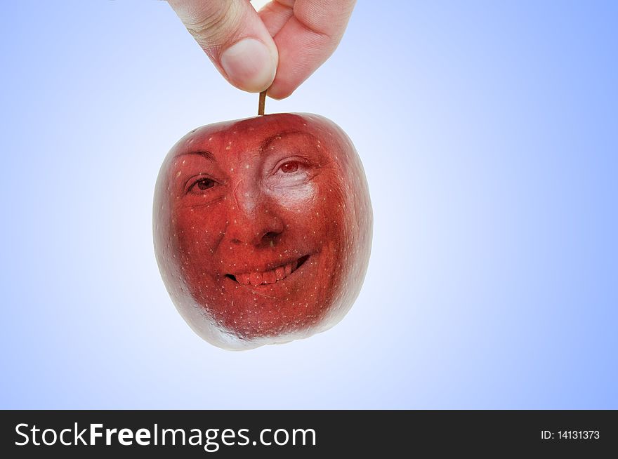 A hand picks a red apple, which also looks just like a cherry with a happy face on it. A hand picks a red apple, which also looks just like a cherry with a happy face on it.