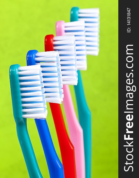 Colored toothbrushes on green background