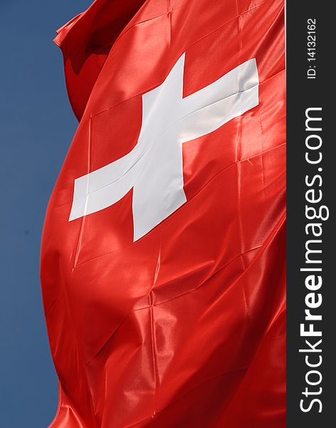 Flag of switzerland in the wind with blue sky. Flag of switzerland in the wind with blue sky