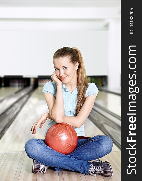 The young attractive girl with a sphere for bowling in the foreground. The young attractive girl with a sphere for bowling in the foreground