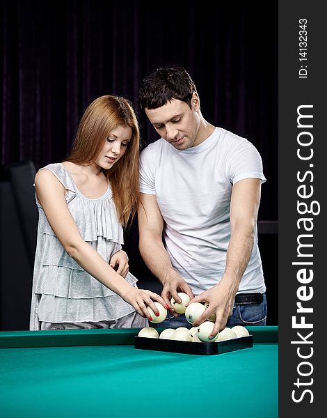 The young attractive couple puts billiard spheres. The young attractive couple puts billiard spheres