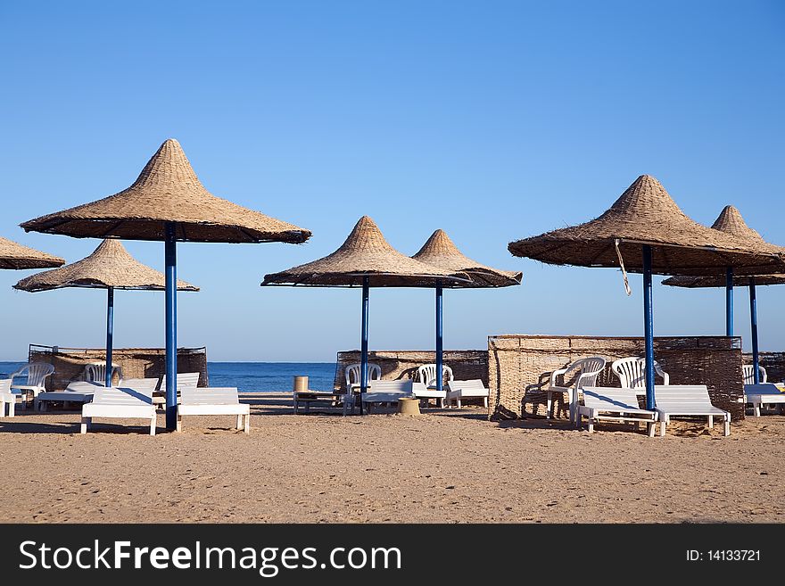 Deck chairs and umbrellas in tropical beach. Deck chairs and umbrellas in tropical beach