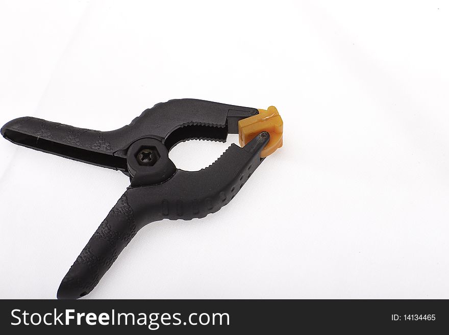 Small black plastic modeling clamp with orange clamp surface on white background