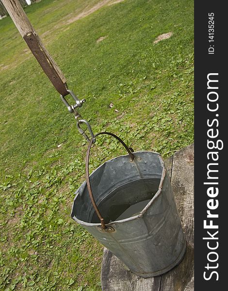 Standing bucket with water standing on farmyard well. Standing bucket with water standing on farmyard well