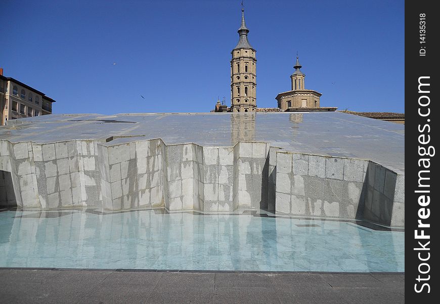 A view of a modern fountain with a church behind, in Zaragoza, Spain. A view of a modern fountain with a church behind, in Zaragoza, Spain.