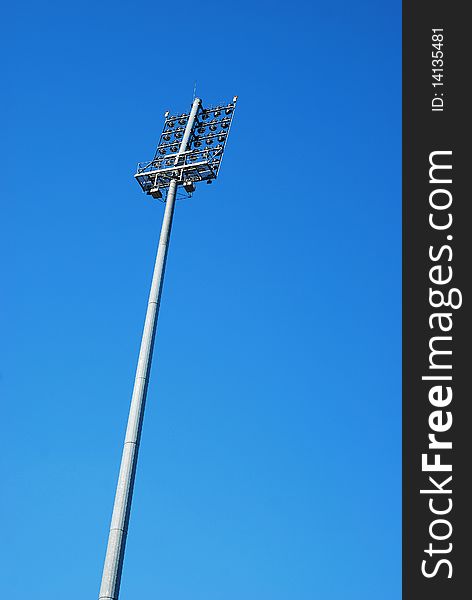 Tall stadium lighting tower over blue sky